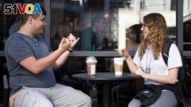 Sign language interpretation major,student Nikolas Carapellatti (L) signs with deaf Gallaudet University student Rebecca Witzofsky outside the first US Starbucks caf<I>&#</i>233; staffed by employees who are partially or fully deaf and capable of communicating in American Sign Language. AFP