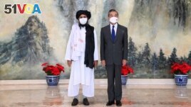 In this photo released by China's Xinhua News Agency, Taliban co-founder Mullah Abdul Ghani Baradar, left, and Chinese Foreign Minister Wang Yi pose for a photo during their meeting in Tianjin, China, Wednesday, July 28, 2021. (Li Ran/Xinhua via AP)