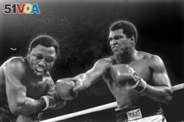 FILE - Spray flies from the head of challenger Joe Frazier as heavyweight champion Muhammad Ali connects with a right in the ninth round of their title fight in Manila, Philippines, Oct. 1, 1974. Ali has died, his family said, June 3, 2016. He was 74.