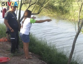 In this Sunday, June 23, 2019 photo, Tania Vanessa <I>&#</i>193;valos of El Salvador speaks with Mexican authorities after her husband and nearly two-year-old daughter were swept away by the current in Matamoros, Mexico, while trying to cross the Rio Grande.
