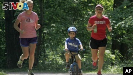 In this 2012 file photo, Andrea Lemastra, right, and Kim Walsh, left, jog on a wooded park trail with Lemastra's four-year-old son, Luca, in the U.S. state of Ohio. (AP Photo/Mark Duncan)
