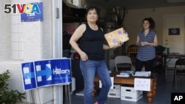 Cynthia Ameli, center, a Chinese-American, picks up materials from Sarah Gibson before heading out to canvass for presidential candidate Hillary Clinton in Las Vegas, Feb. 12, 2016.