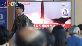 A South Korean army soldier passes by a TV screen showing a file image of North Korea's missile launch during a news program at the Seoul Railway Station in Seoul, South Korea, Tuesday, Aug. 6, 2019.