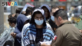 FILE - 墨西哥官员和美国边境巡逻官员按照名单将一群移民送返墨西哥（2019年7月25日）