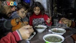 Displaced Palestinian man Wael Al-Attar eats Khobiza, a wild leafy vegetable, with his family as they break their fast during the holy month of Ramadan, at a school where they shelter, in Jabalia in the northern Gaza Strip, March 22, 2024. (REUTERS/Mahmoud Issa)