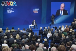 Russian President Vladimir Putin, sitting on the stage at centre rear, speaks to his supporters during a meeting for his campaign in Moscow, Jan. 30, 2018.
