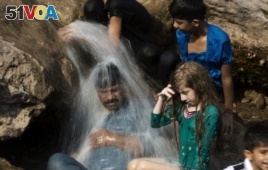 FILE - A family cools off in a stream during a heat wave, in Islamabad, Pakistan, May 30, 2017. The town of Turbat in southwestern Pakistan reported a temperature of 54 degrees Celsius in May.