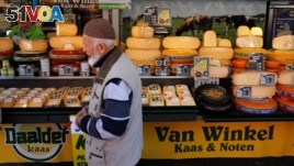 FILE - A man walks by a cheese stall at a market in The Hague, Netherlands.