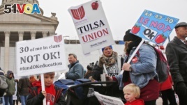 Keagan Nedrow, left, and Reed Nedrow, bottom right, stand with their mother, Tara Nedrow, right, who teaches history at Union High School, and other teachers, during a teacher rally against low school funding at the state Capitol Oklahoma City, Monday, Ap