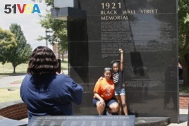Katrina Cotton, center, of Houston, poses for a photo with her daughter, Kennedy Cotton, age seven, as her aunt, Janet Wilson, left, takes the photo, at the Black Wall Street memorial in Tulsa, Okla., Monday, June 15, 2020. (AP Photo/Sue Ogrocki)