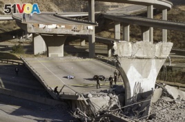 FILE - In this Jan. 17, 1994, file photo, the covered body of Los Angeles Police Officer Clarence Wayne Dean lies near his motorcycle which plunged off the State Highway 14 overpass that collapsed onto Interstate 5, after the Northridge earthquake.