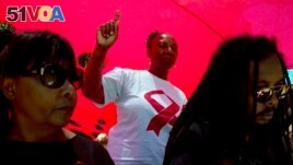 FILE - A woman dances as she listens to music while attending a World AIDS Day commemoration at Nkosi's Haven in Johannesburg on Nov. 30, 2019 on the eve of World AIDS Day. (AP Photo/Denis Farrell, File)