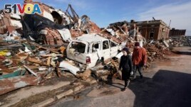People survey damage from a tornado in Mayfield, Ky., on Saturday, Dec. 11, 2021. (AP Photo/Mark Humphrey)