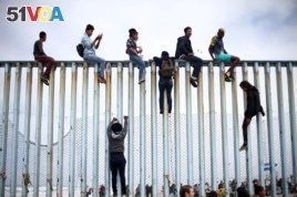 Members of a caravan of migrants from Central America climb up the border fence between Mexico and the U.S., as a part of a demonstration prior to preparations for an asylum request in the U.S., in Tijuana, Mexico April 29, 2018.