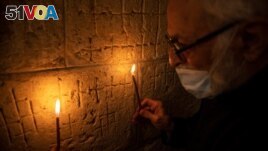 Father Samuel Aghoyan, the Armenian superior at the Church of the Holy Sepulchre, holds candles to illuminate crosses etched into the ancient stone wall of the Saint Helena chapel inside the church. (REUTERS/Ronen Zvulun)