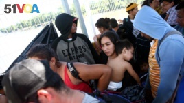 Central American migrants line up at a bridge that connects Guatemala to Mexico.