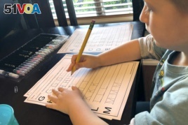 In this March 24, 2020, photo provided by Christina Rothermel-Branham, her son James, does school work at their Tahlequah, Okla. home.