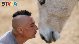 Zeljko Ilicic kisses a horse in the Old Hill, sanctuary for horses in the town of Lapovo, in central Serbia, Wednesday, April 3, 2024. (AP Photo/Darko Vojinovic)