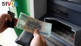 FILE - A man withdraws money from an ATM at a branch of Vietnam Prosperity Joint Stock Commercial Bank (VPBank) in Hanoi, Nov. 15, 2017. 