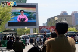 North Koreans watch as their country's most famous newscaster announces leader Kim Jong Un's proposal to suspend nuclear tests and long-range missile launches on a giant screen on Pyongyang's newly built Mirae Scientists' Street.