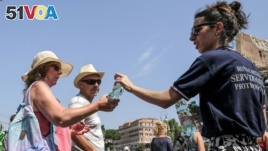 Members of the Italian Civil Protection (Protezione Civile) give water bottles to people and tourists in front of the Ancient Colosseum in central Rome. Italy experienced a heatwave in August 2018. (AFP PHOTO / Andreas SOLARO)
