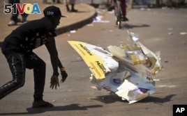 An angry voter smashes a campaign placard of long-time President Yoweri Museveni, outside a polling station where voting material for the presidential election never arrived, at a polling station in Ggaba, on the outskirts of Kampala.