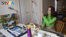 In this Wednesday, April 22, 2020, photo, knitwear designer Felicia Lynch works on her knitting machine at her dinning room table in the Williamsburg neighborhood of the Brooklyn borough of New York. (AP Photo/Mary Altaffer)