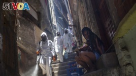 Volunteers spray disinfectant in an alley to help contain the spread of the new coronavirus at the Santa Marta slum in Rio de Janeiro, Brazil, Saturday, Nov. 28, 2020.