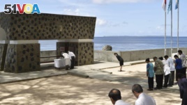 FILE - Emperor Akihito, top right, and Empress Michiko, top left, offer flowers in front of a memorial for Japanese victims on Pelelilu island in Palau April 9, 2015.