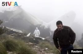 An investigator (back) works near the wreckage of a military plane which crashed near the village of Ouled Gacem in eastern Algeria, about 500km (311 miles) from the capital Algiers on February 12, 2014. The military transport plane carrying members of the Algerian armed forces and their relatives crashed into a mountain, killing 77 people, the worst air disaster in the North African country in a decade. (REUTERS/Louafi Larbi)