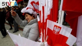 华沙街头一名小贩出售带有国徽的波兰国旗庆祝该国的宪法日。（2017年5月3日）