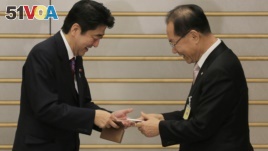 South Korea's ruling Saenuri Party chairman Hwang Woo-yea, right, and Japanese Prime Minister Shinzo Abe exchange their business cards prior to their meeting at the prime minister's residence in Tokyo, Wednesday, Jan. 9, 2013. (AP Photo/Itsuo Inouye, Pool)
