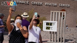 People take selfies at the Furnace Creek Visitor Center thermomete, Aug. 17, 2020, in Death Valley National Park, California.