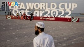 A man is pictured in front of a FIFA World Cup Qatar 2022 sign on November 17, 2022. (REUTERS/Marko Djurica)