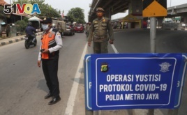 Officers stand guard at a police check point as the large-scale restriction is imposed to curb the spread of the coronavirus outbreak in Jakarta, Indonesia, Monday, Sept. 14, 2020.