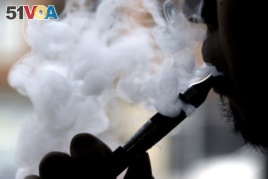 In this April 23, 2014 file photo, a man smokes an electronic cigarette in Chicago. On Friday, Aug. 30, 2019, the Centers for Disease Control and Prevention said they are investigating more cases of a breathing illness associated with vaping.