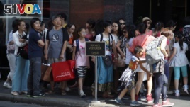 FILE - Chinese tourists line up to enter a fashion store in Paris Aug. 12, 2015. (AP Photo/Francois Mori)