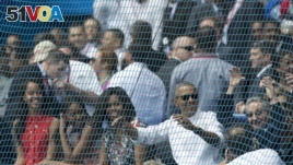 Cuban President Raul Castro, right, cheers next to U.S. President Barack Obama, his wife Michelle, and their daughters Sasha and Malia, at the start of a baseball game between the Tampa Bay Rays and the Cuban national baseball team, in Havana, Cuba, Tuesd