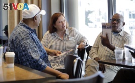 In this photo taken Monday, June 10, 2019, Seattle City Council candidate Pat Murakami, center, talks with voters in a coffee shop about her campaign in Seattle. (AP Photo/Elaine Thompson)
