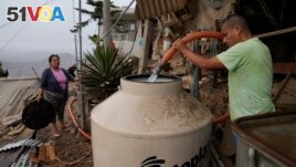 Alfonso Tapullima, right, fills the water tank near his wife Justina Flores, at the Pamplona Alta hilltop neighborhood in Lima, Peru, Friday, March 8, 2024. (AP Photo/Martin Mejia)