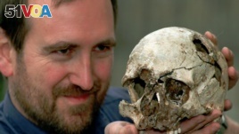 FILE - Dr. Chris Stringer the principal researcher of human origin at the Natural History Museum in London with the skull of Cheddar Man, a 9,000-year-old skeleton, March 7, 1997. (AP Photo/Michael Stephens)