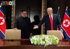 FILE PHOTO: U.S. President Donald Trump and North Korea's leader Kim Jong Un (L) arrive to sign a document to acknowledge the progress of the talks.