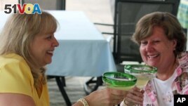 This May 31, 2013 photo shows baby boomers Benita Munger, left, and Judy Palladino toasting during a game night gathering in Mayfield Village, Ohio. 