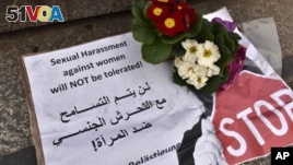 A banner with flowers is placed on the steps to the Cologne cathedral reading in English and Arabic 