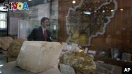 An Afghan journalist walks by an exhibit of minerals on the way to a news conference by the Afghan Minister of Mines in Kabul, Afghanistan, June 17, 2010