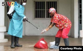 A Liberian Red Cross employee disinfects after removing a body suspected of having Ebola, Monrovia, September 2014. (Credit: International Alert)