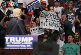 FILE - Republican presidential candidate Donald Trump, left, looks on as one of his supporter reaches for a sign that reads 