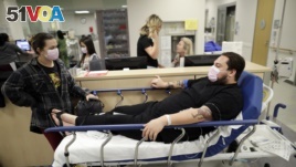 Donnie Cardenas, right, waits in an emergency room hallway alongside roommate Torrey Jewett, left, as he recovers from the flu at the Palomar Medical Center in Escondido, Calif., on Wednesday, Jan. 10, 2018. (AP Photo/Gregory Bull)
