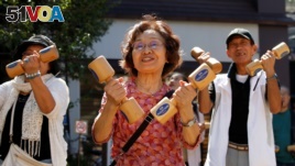 Elderly and middle-aged people exercise with wooden dumbbells during a health promotion event to mark Japan's 