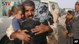 Abdul Rahman Ismail, an Iraqi soldier who has been targeted by Islamic State extremists who destroyed his house two years ago, is reunited with his family after they were able to flee their Islamic State held town, as displaced Iraqi families gather outside. (AP)